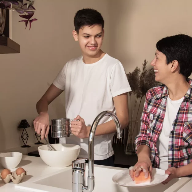 Support worker and young person cooking and cleaning together