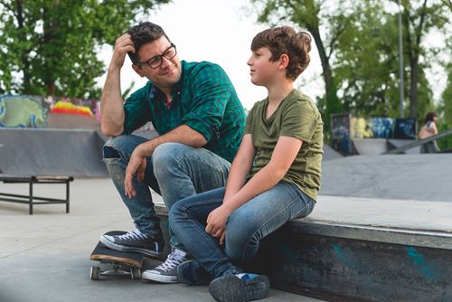 Support worker sat with young person at skate park