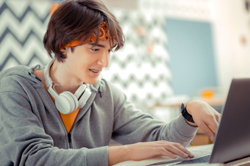 Young person on laptop with headphones around neck