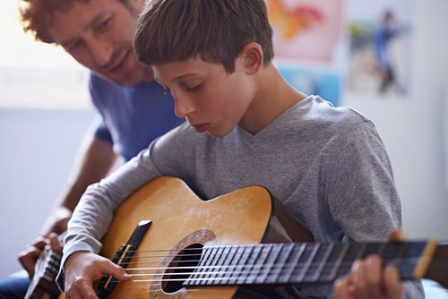 Young person playing guitar with support worker